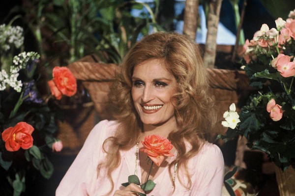 Dalida assise souriante entourée de fleurs